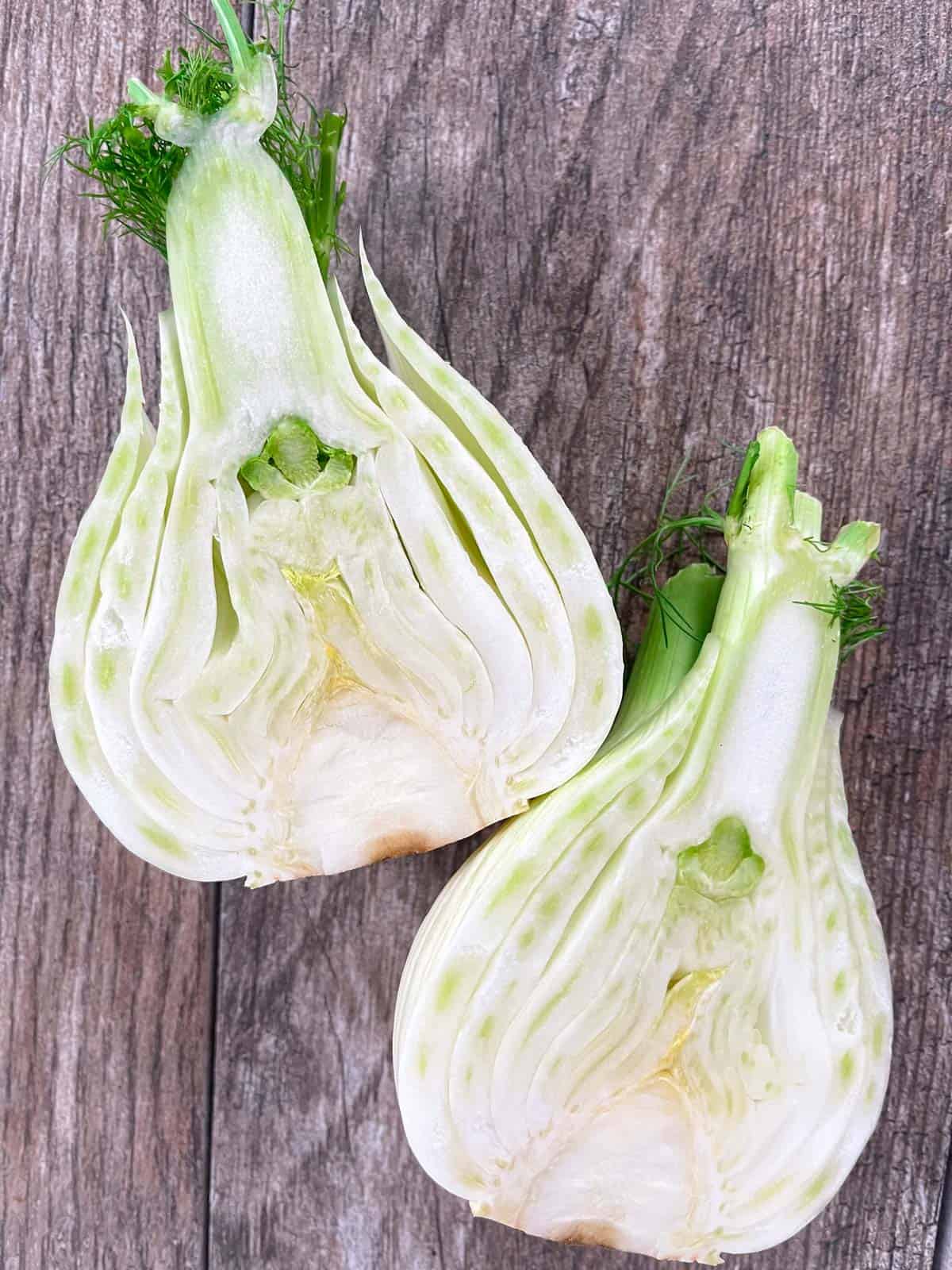 Fennel bulb cut in half on a wood background.