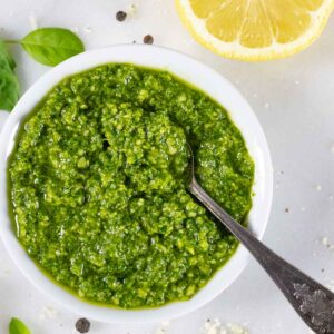 Pesto without pine nuts in a ramekin with a silver spoon in it.