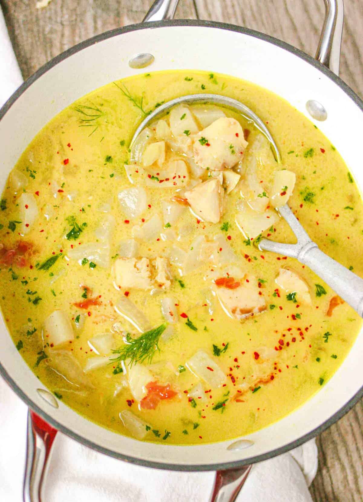 Fish soup with turnip and fennel in a pot with a ladle and ready to serve.