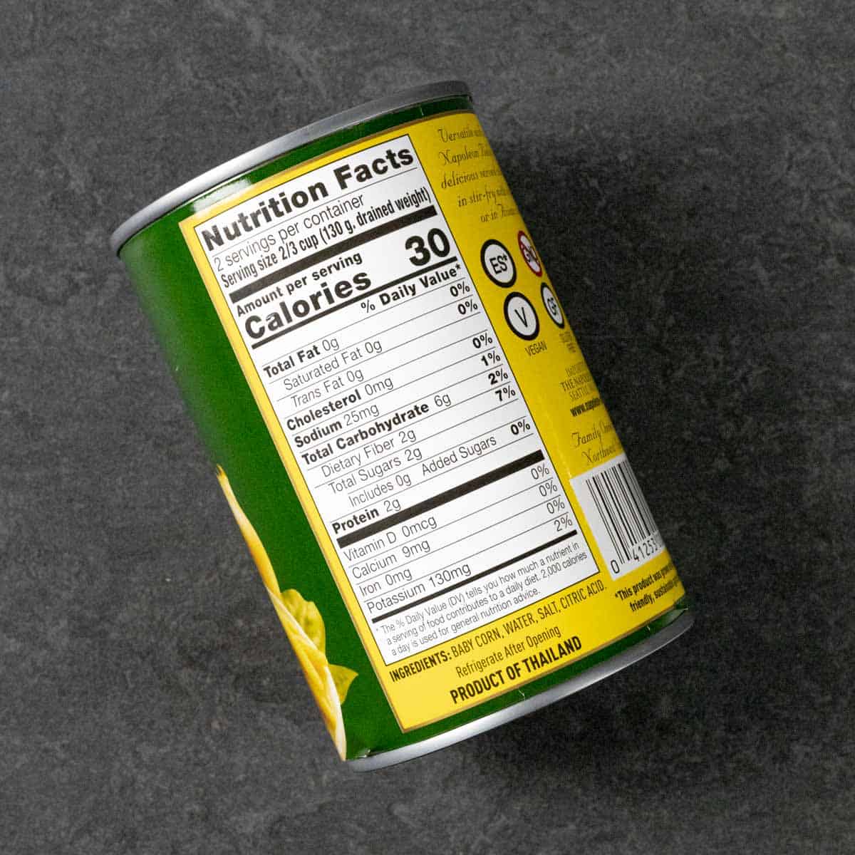 Can of baby corn cobs showing nutrition label on a grey board.