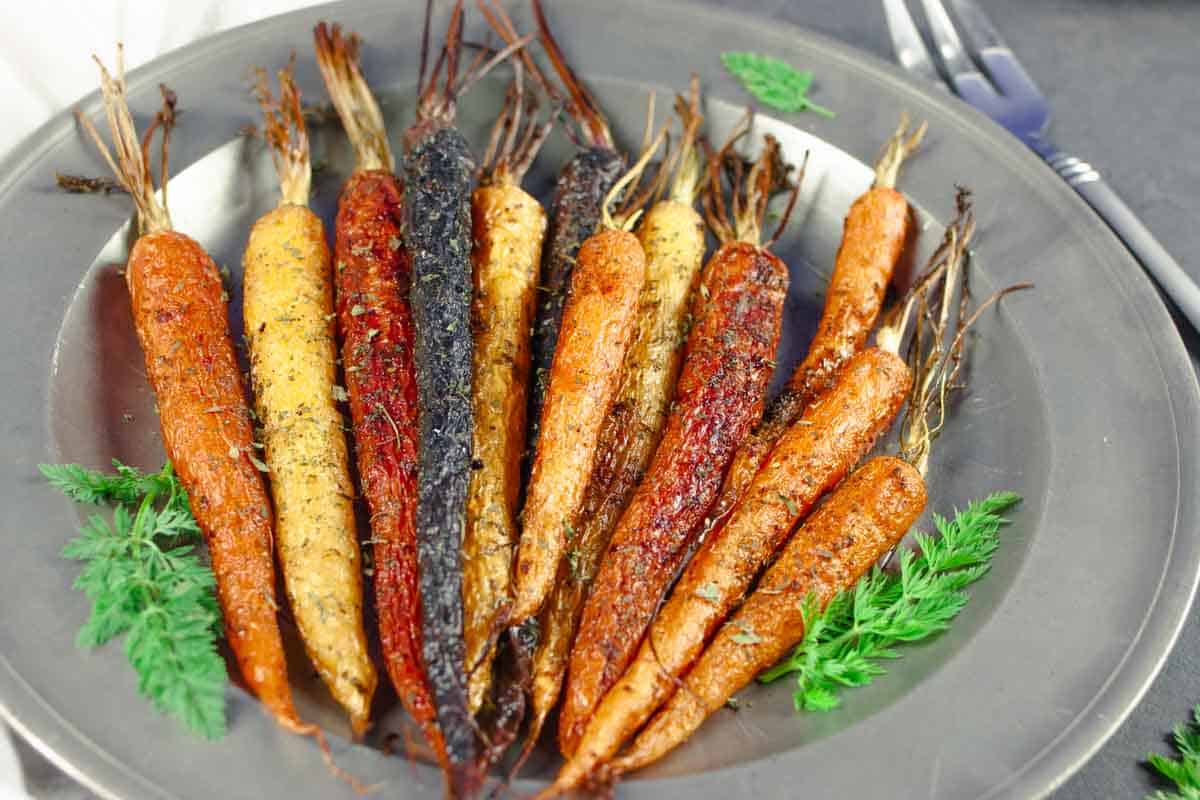 Roasted carrots on a pewter plate and serving fork.
