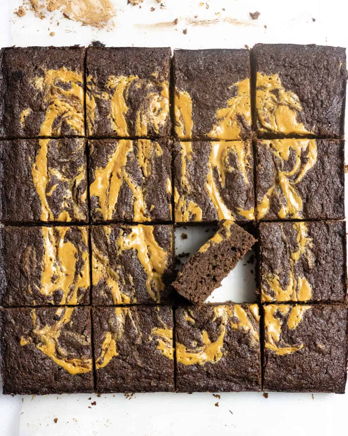 Brownies with peanut butter swirls cut into squares with one on edge.