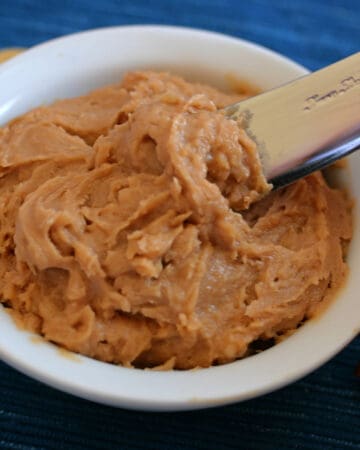 Small bowl of peanut butter cream cheese frosting with butter knife.