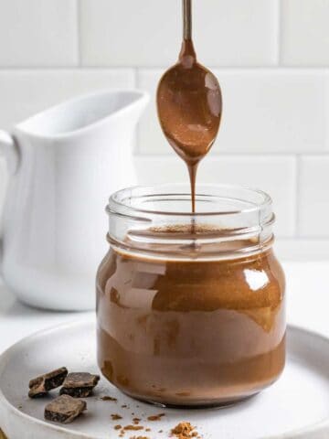 Jar of coconut milk chocolate sauce with a spoonful streaming into the jar.