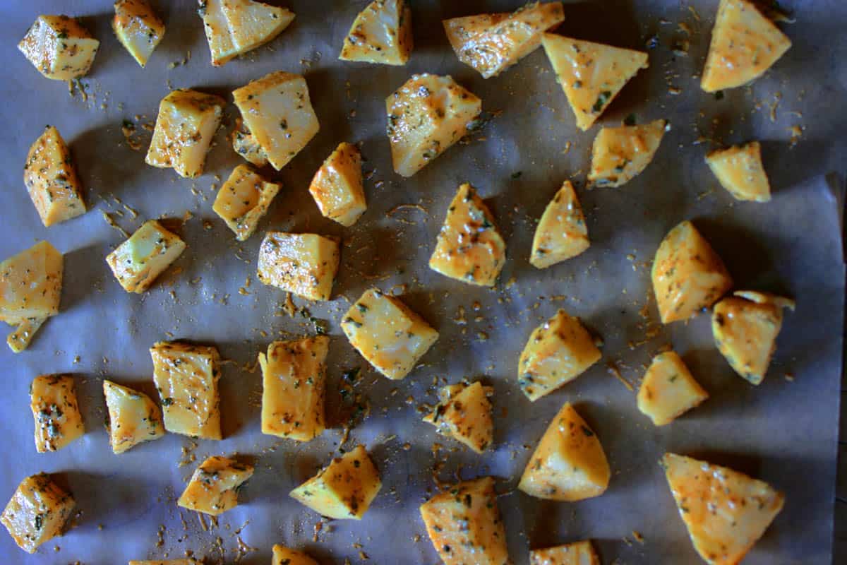 Raw chunks of seasoned rutabaga on baking sheet ready to roast.