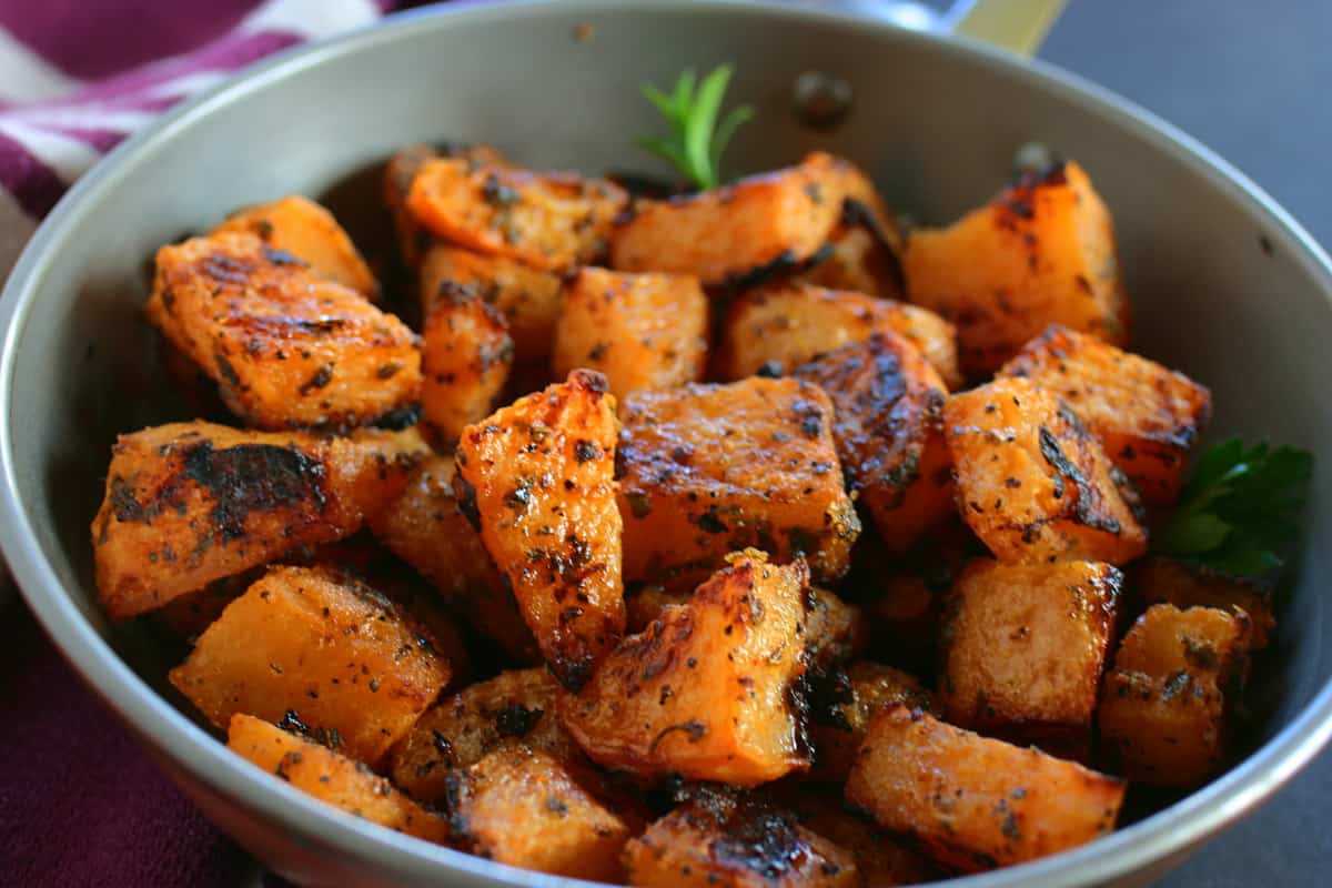 Bowl of roasted chunks of rutabaga with garnish.