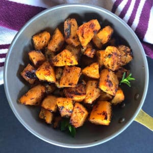 Herb roasted rutabaga in a small copper skillet with a towel.