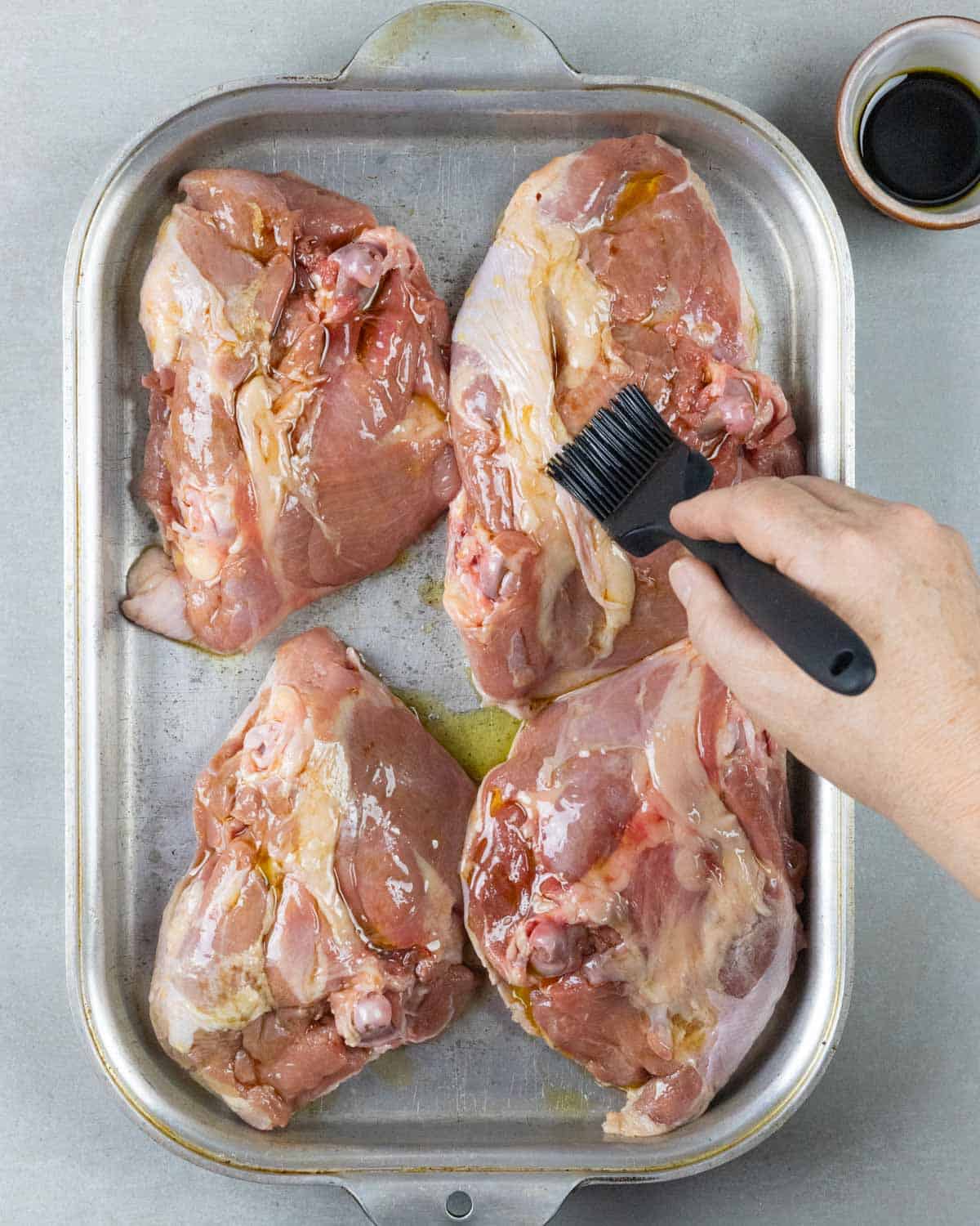 Basting underside of thighs with olive oil and balsamic with a basting brush.