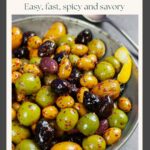 Spicy marinated olives of several varieties in a pewter serving dish sprinkled with Aleppo pepper.