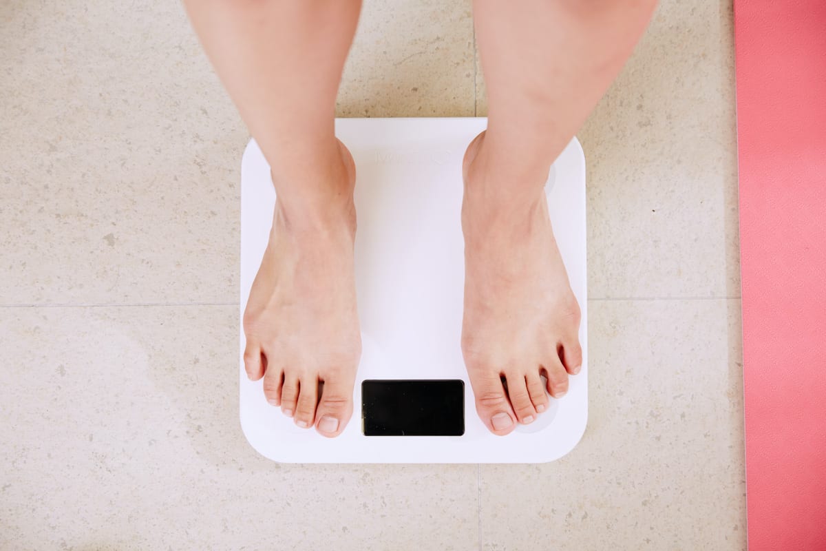 Barefoot person from knees down standing on a white scale.