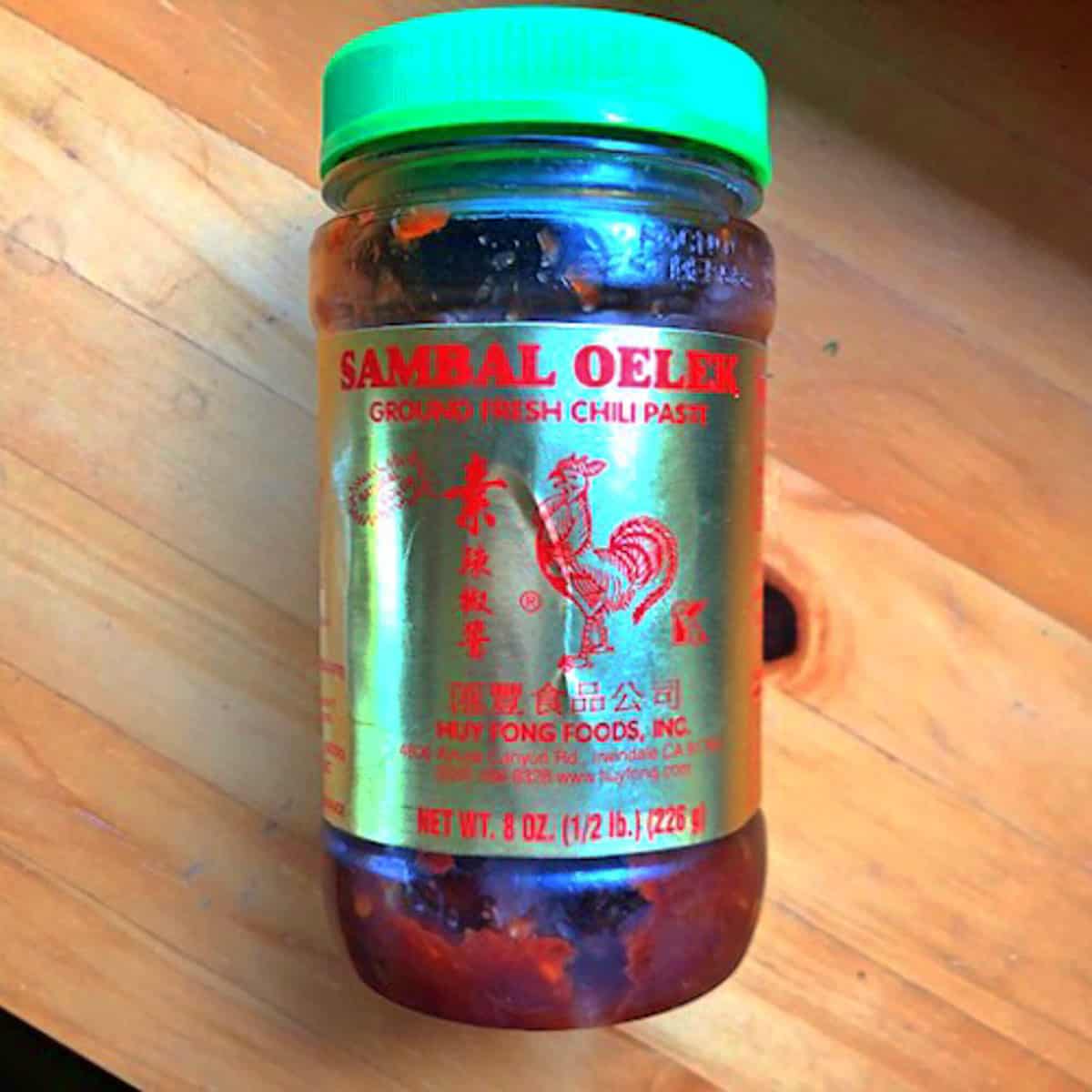 Sambal Oelek chili paste small bottle on a wood background.