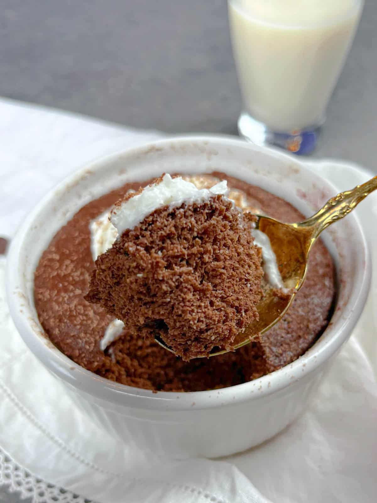 Low carb mug cake with a bite scooped out on a gold spoon.