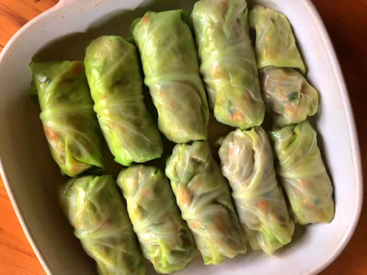 Cabbage rolls before baking, in baking pan before the peanut sauce is poured on.