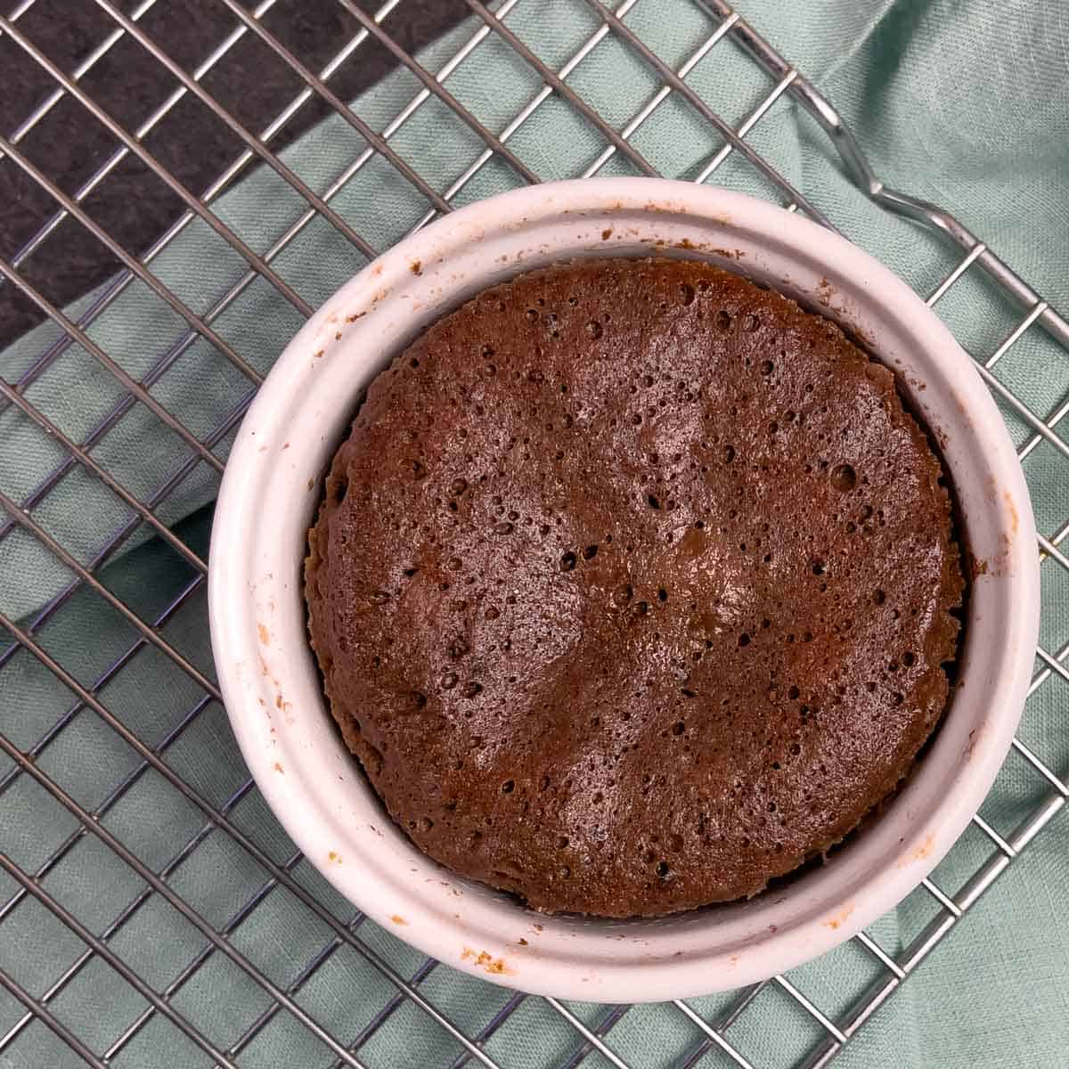 Cooked mug cake in a ramekin on a cooling rack.