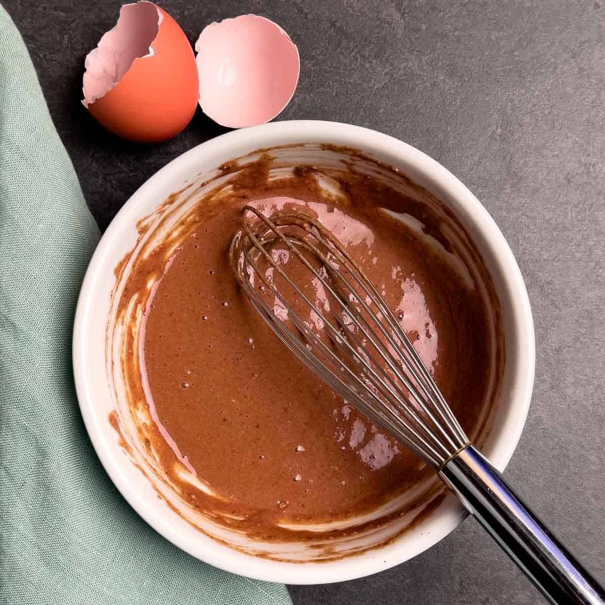 Mug cake ingredients mixed in a bowl with a whisk.