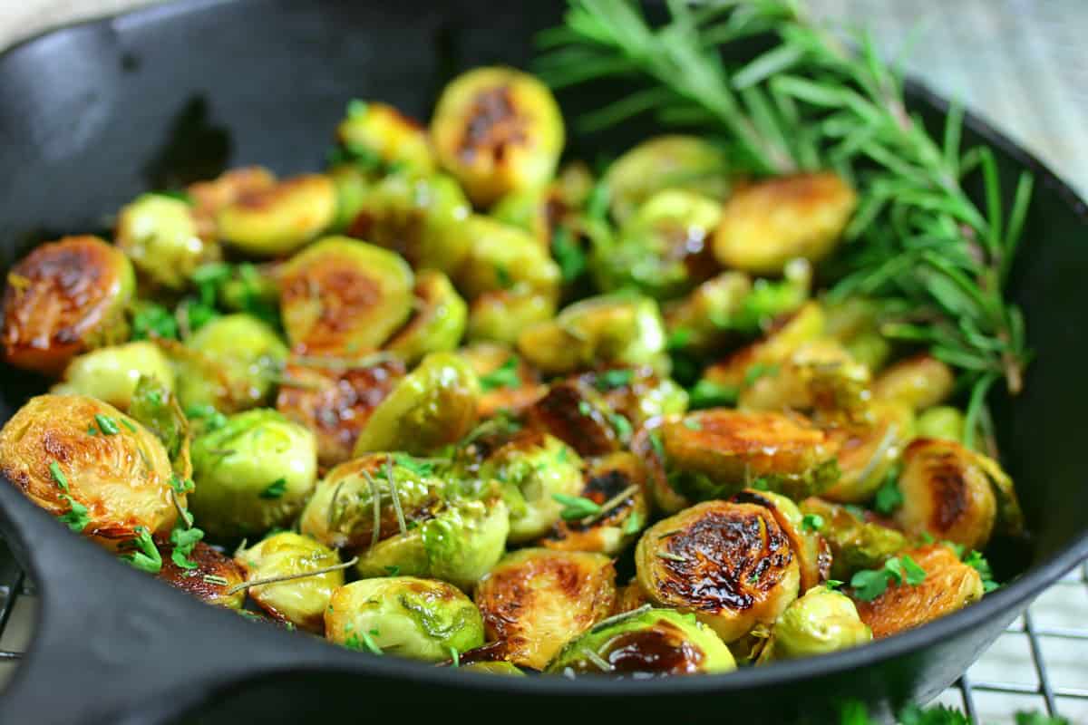 Close up of Brussels sprouts in a cast Iron skillet with rosemary.