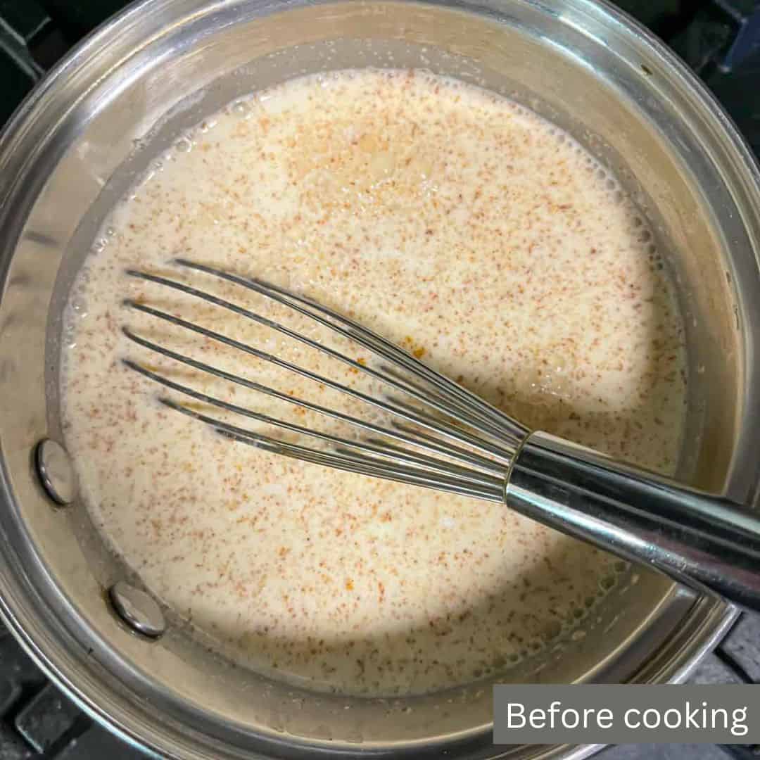 Keto eggnog in a saucepan with a whisk showing ingredients before cooking with label.