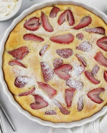 Low carb berry clafoutis fully baked in a tart dish sprinkled with keto sweetener.