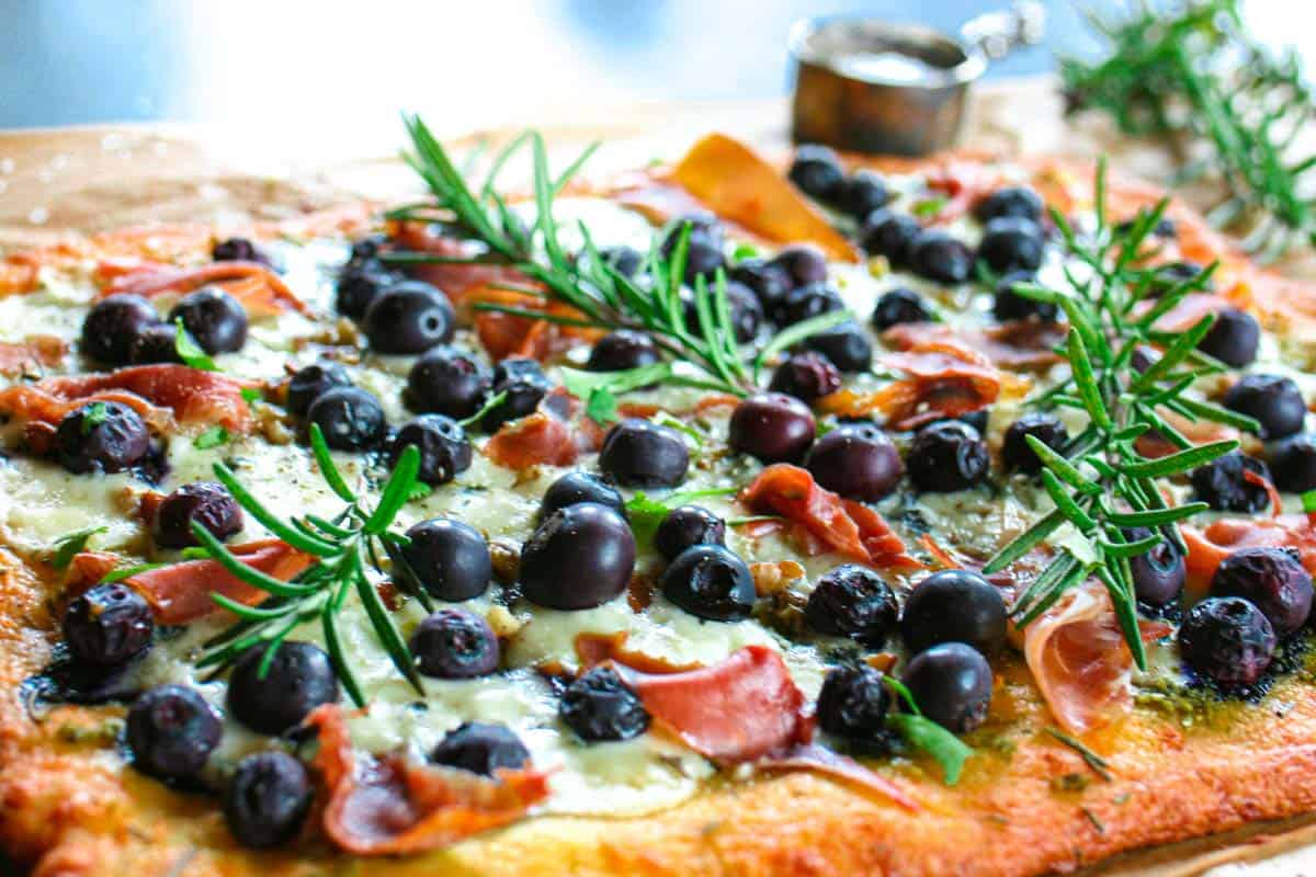 Blueberry pizza with sprigs of fresh rosemary on top.