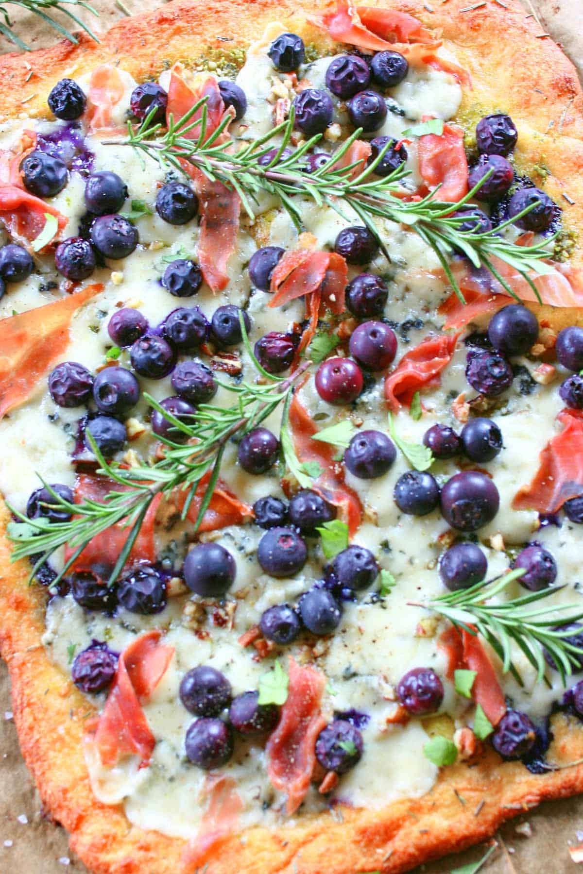 Blueberry pizza with blueberries and fresh rosemary sprigs on top.