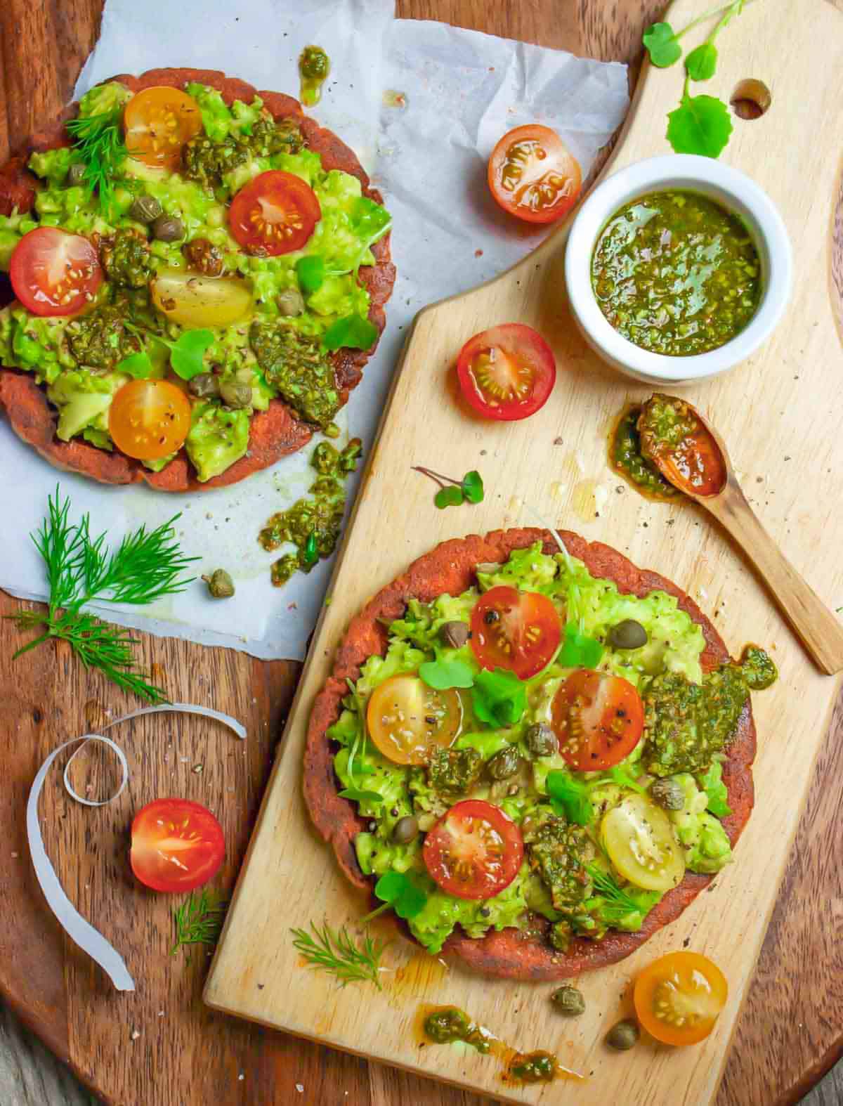 Guacamole on avocado toast with a side of pesto and topped with tomatoes.