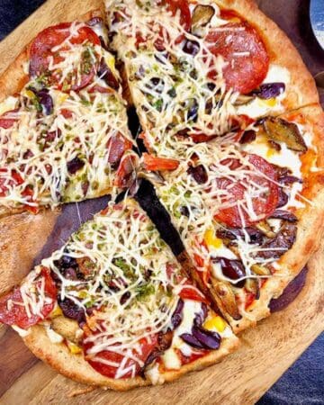 Keto fathead dough pizza crust topped with pepperoni, cheese and olives, cut into four slices.