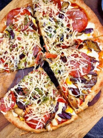 Keto fathead dough pizza crust topped with pepperoni, cheese and olives, cut into four slices.
