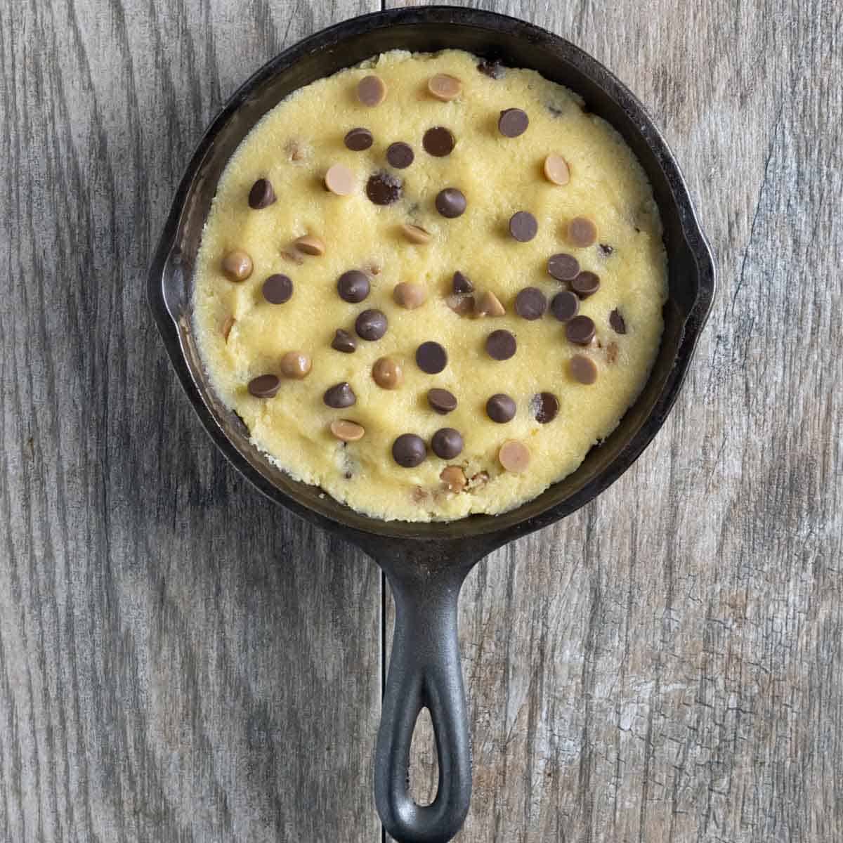 Mini cookie dough spread in a cast iron mini skillet sprinkled with chocolate and butterscotch chips.
