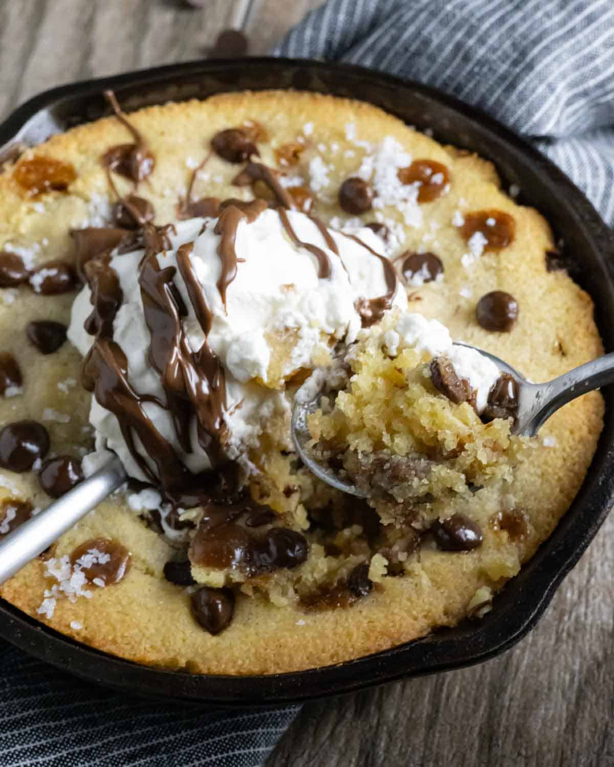 Chocolate chip skillet cookie topped with whipped cream and chocolate drizzle.