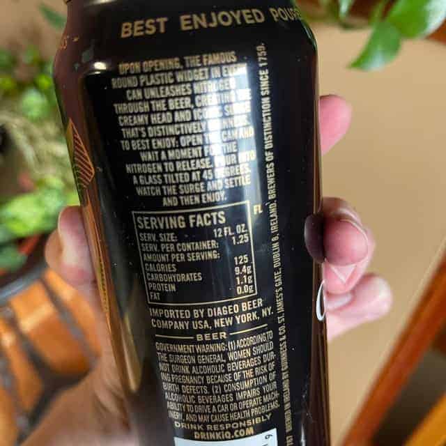 Hand holding can of Guinness beer showing back of label.