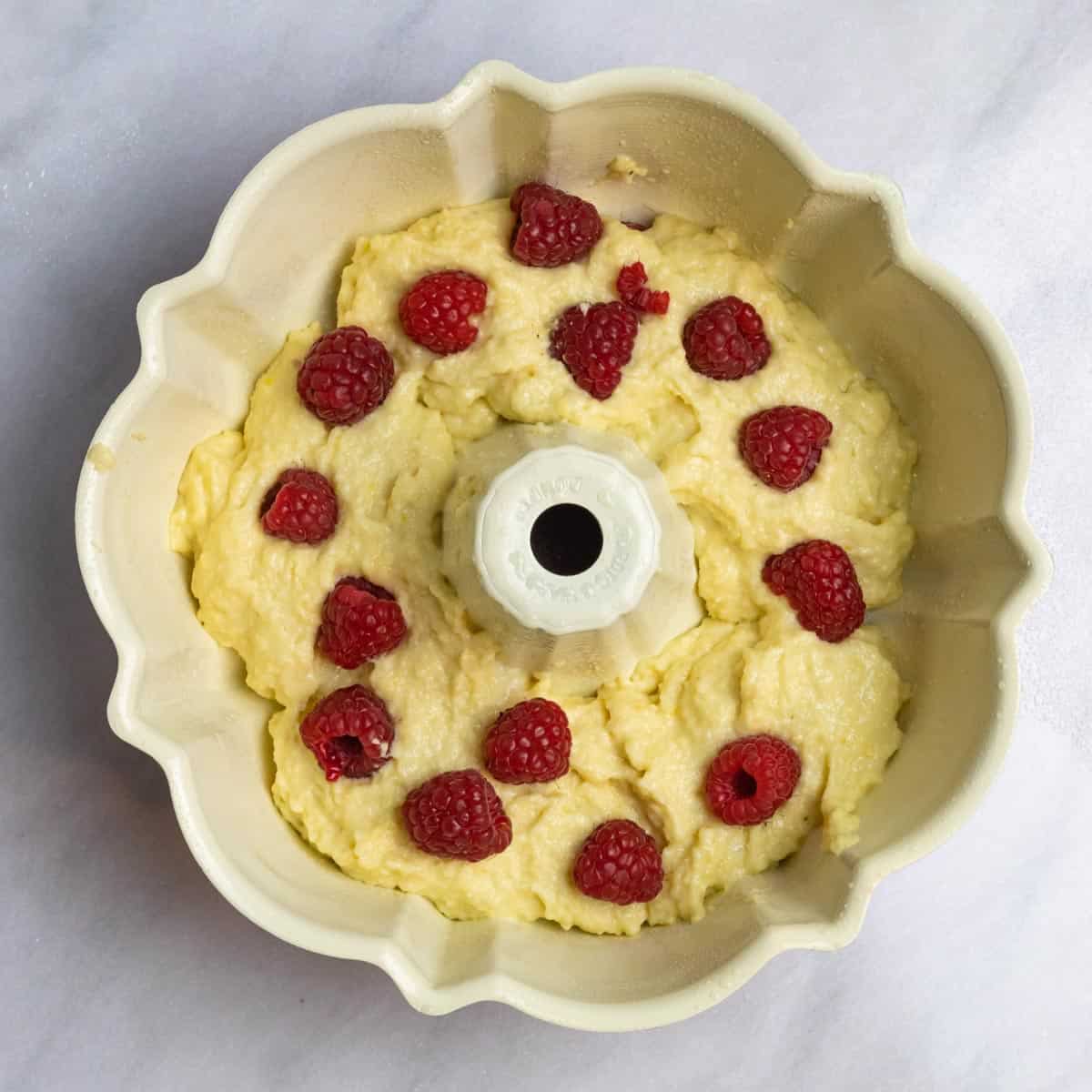 Layer of batter in bundt cake pan with fresh raspberries on to to create middle layer.