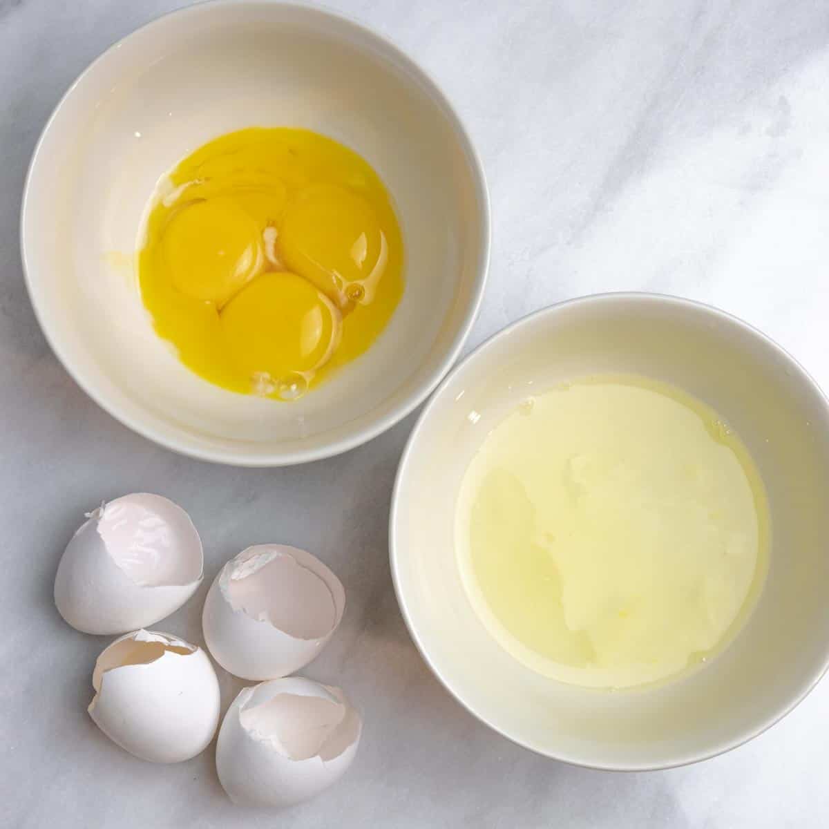 Step showing two bowls with egg whites in one, and yolks in the other.  Cracked egg shells are next to the bowls.