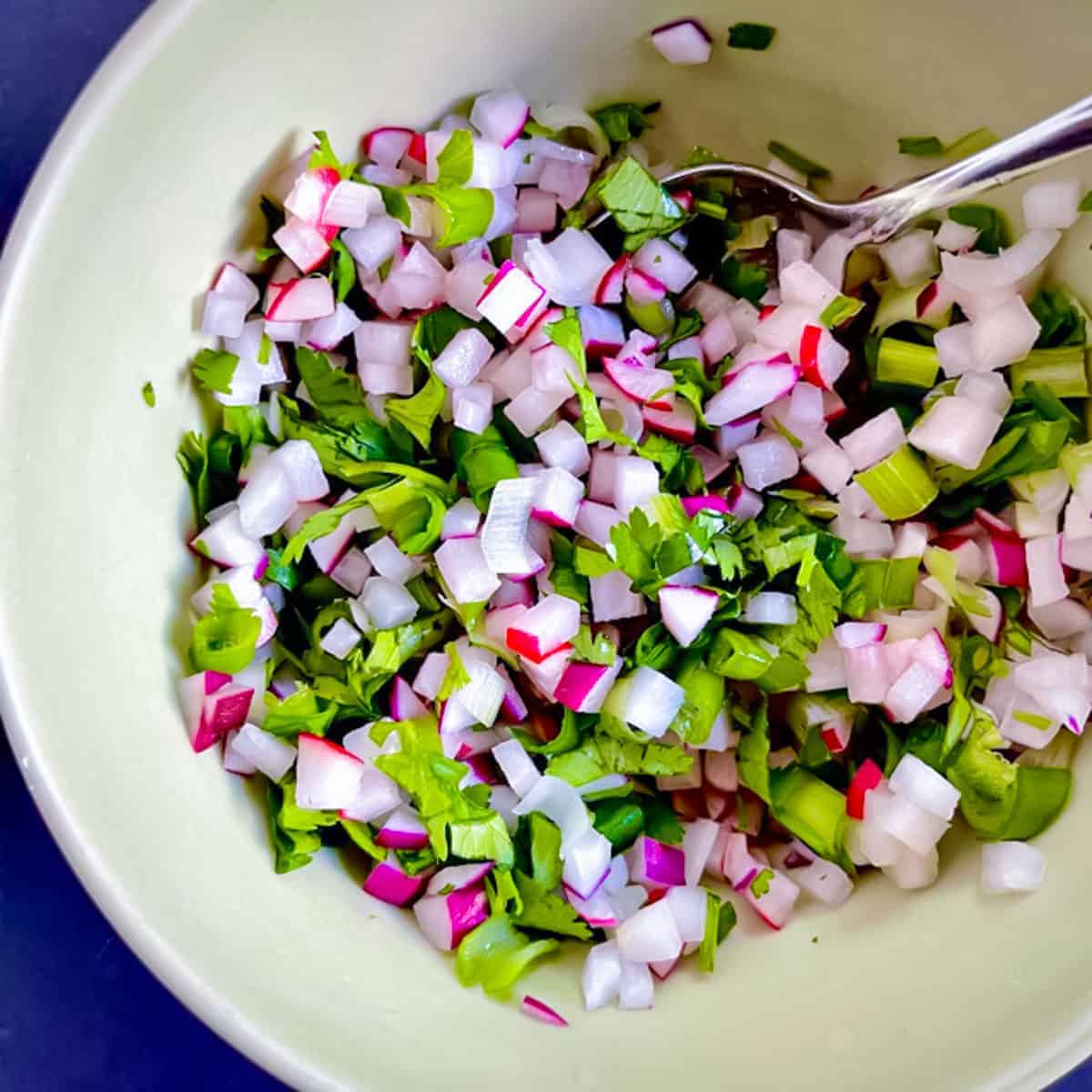 Radish salsa in a yellow bowl with a spoon.