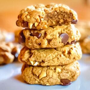 Stack of four peanut butter chocolate chip cookies, with the top one missing a bite.