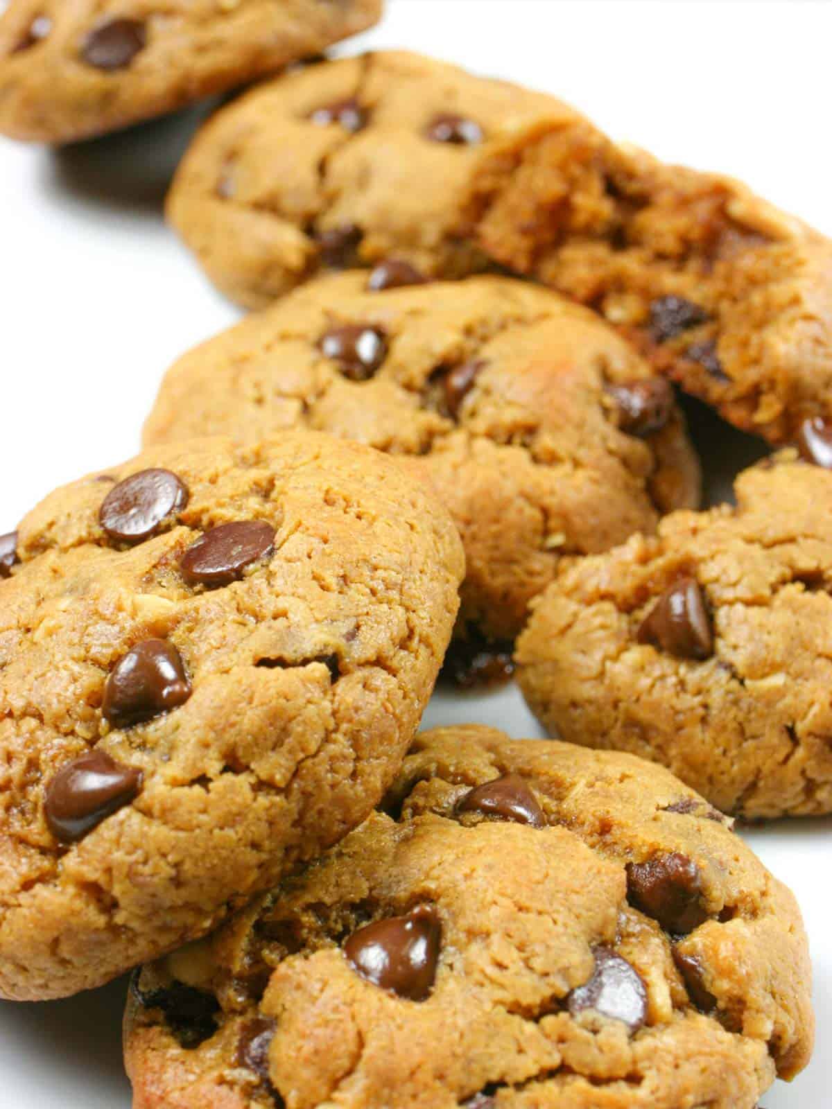 Pile of gluten free peanut butter chocolate chip cookies on a white background.