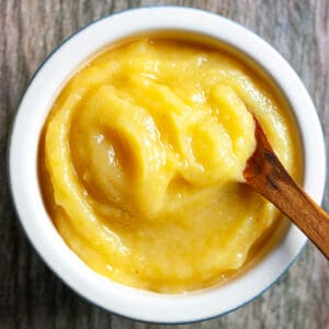 Preserved lemon puree in a small white bowl with a wooden spoon scooping some out.