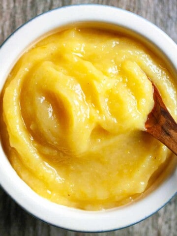 Preserved lemon puree in a small white bowl with a wooden spoon scooping some out.