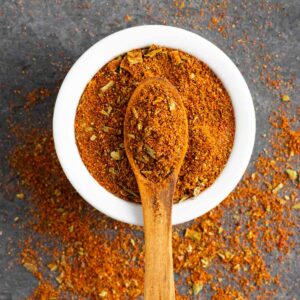 Taco seasoning in a small bowl with small wooden spoon in the center covered in spice.