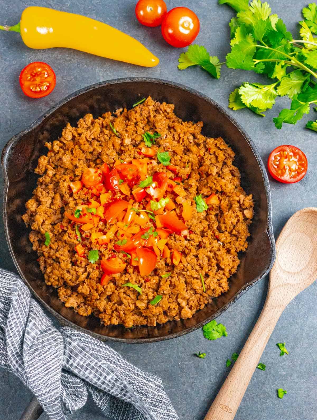 Low-FODMAP taco meat in a cast iron skillet topped with tomatoes and peppers