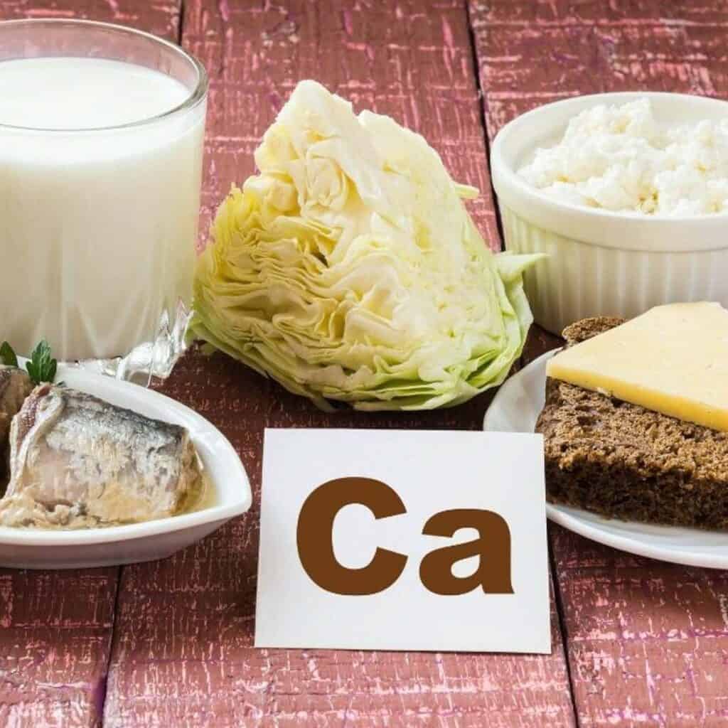 Dairy and veggies on a brick colored background with a card showing the periodic table letters for calcium.