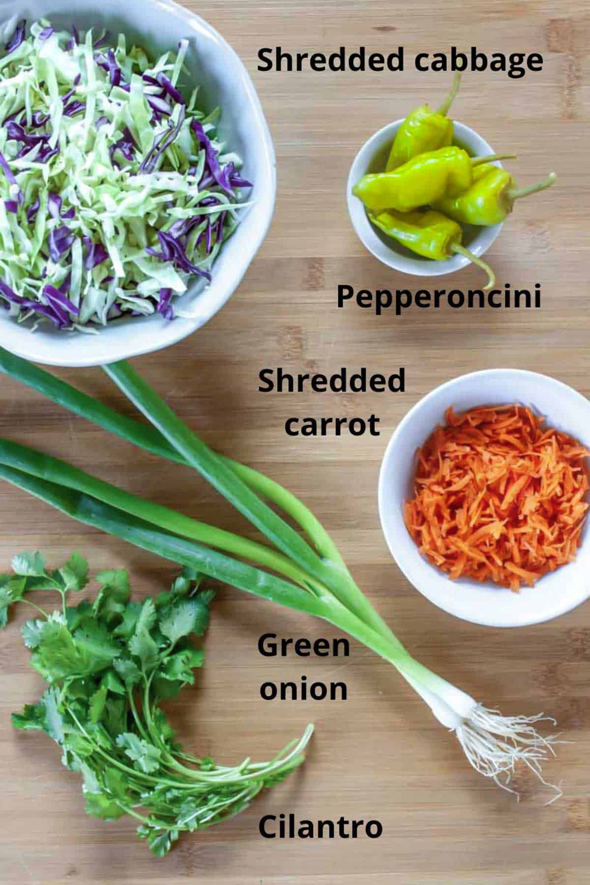 Ingredients for coleslaw on a board with black text labels.