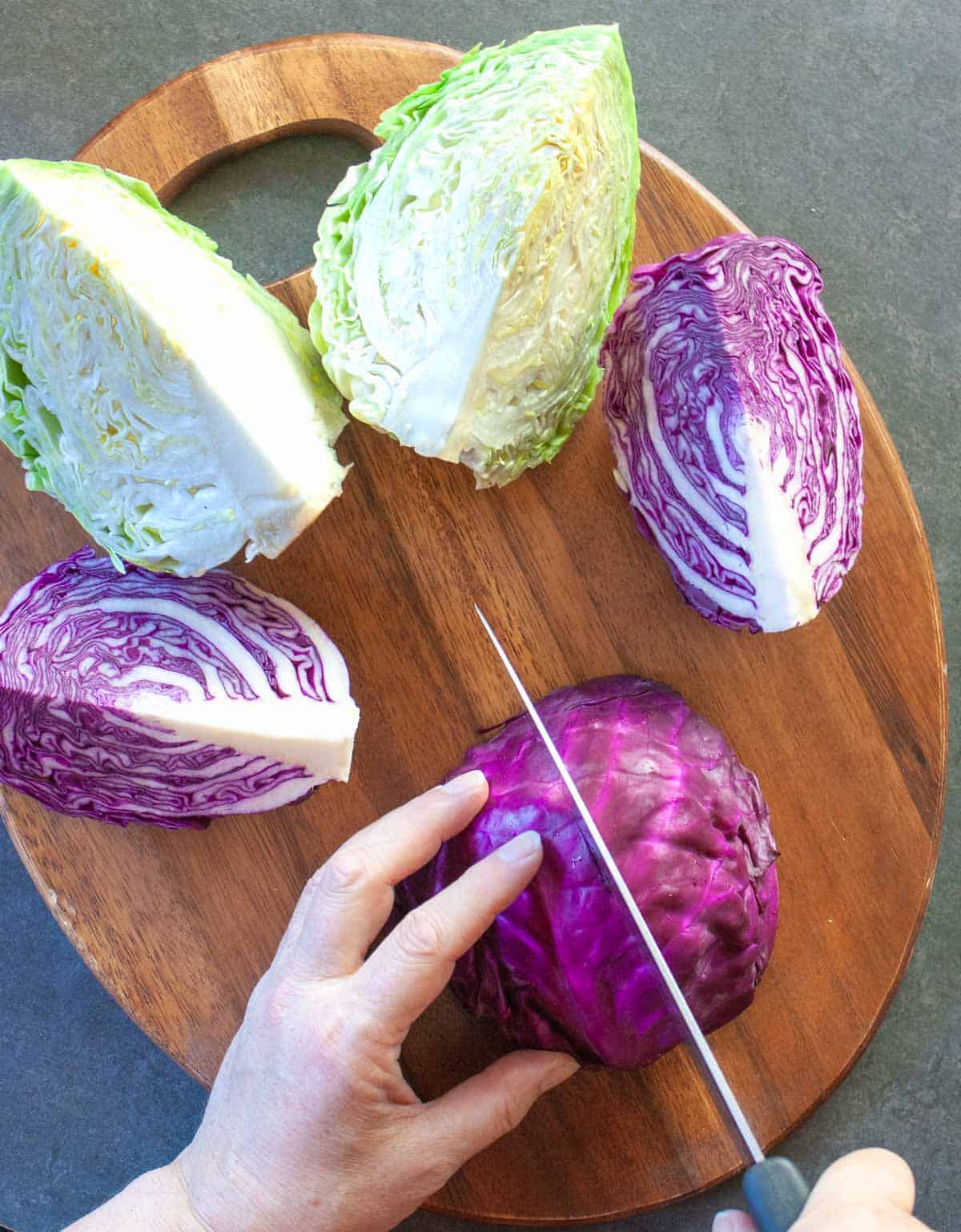 Slicing a red cabbage half head into quarters with a knife.