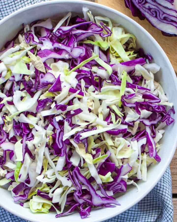 Red and green shredded cabbage in a white bowl.