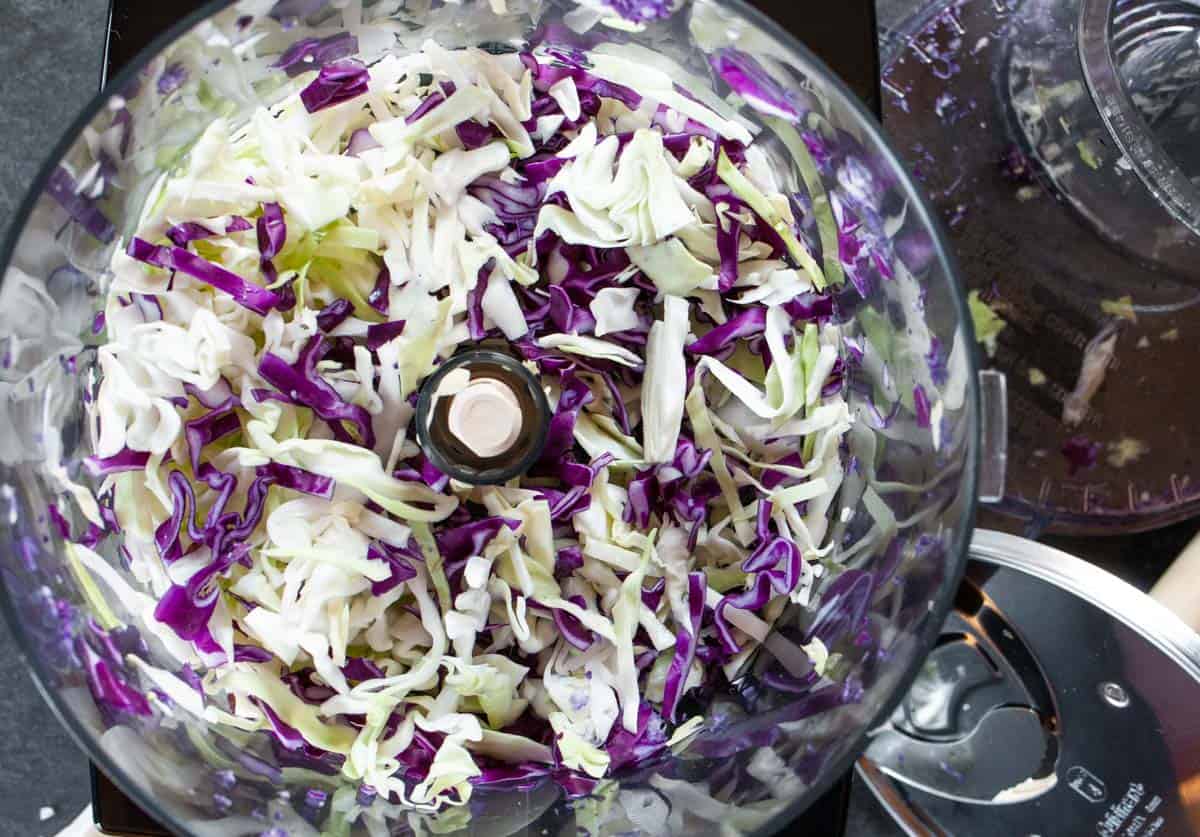 Sliced green and red cabbage in food processor bowl using slicer attachment.