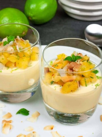 Pina colada panna cotta in serving glasses topped with pineapple salsa and toasted coconut.