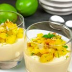 Two glasses of panna cotta topped with pineapple, toasted coconut flakes and a mint leaf.