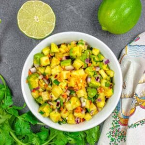 Bowl of Pineapple habanero salsa with lime and cilantro garnish.