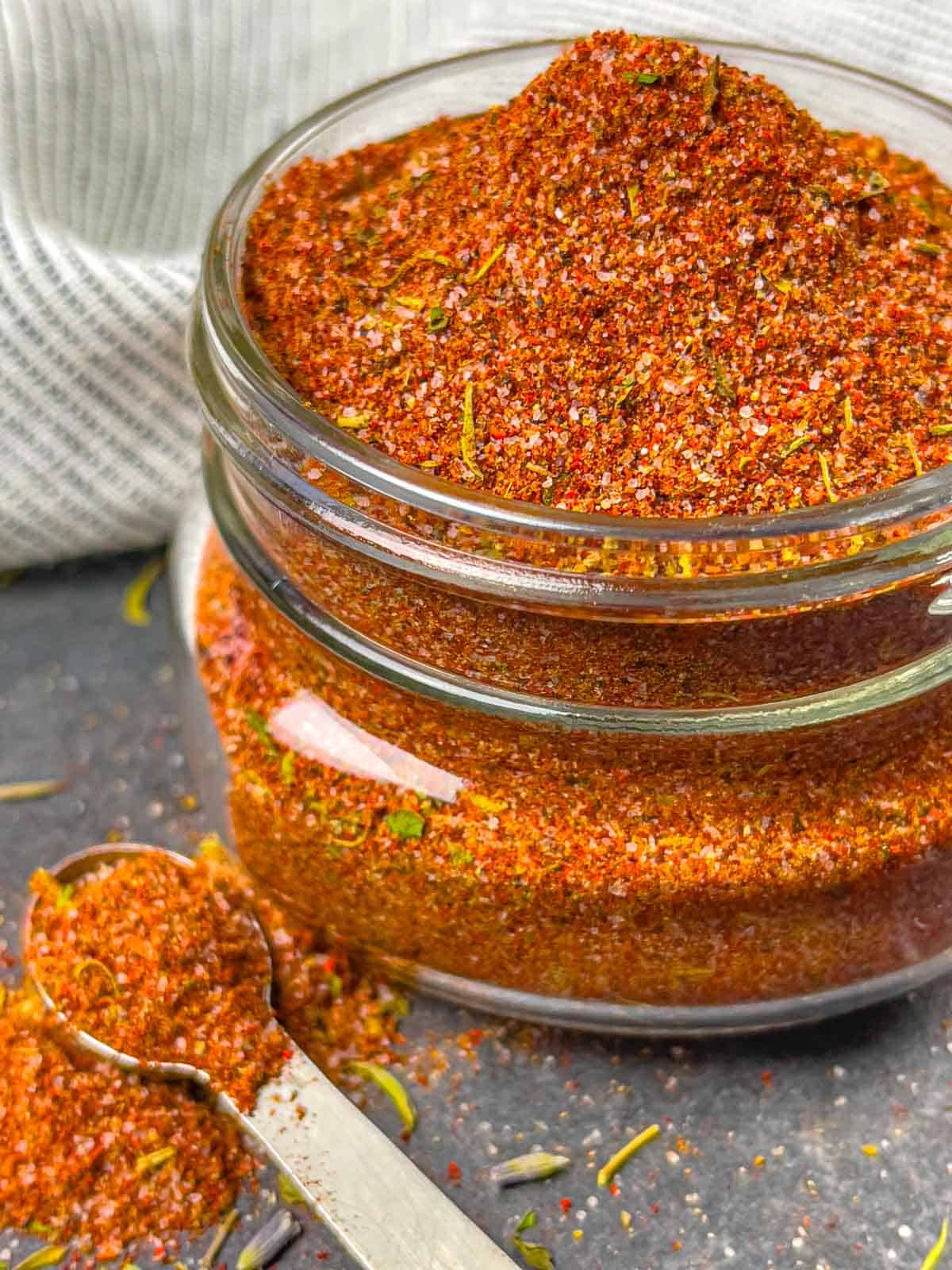 Jar of keto barbeque seasoning with a spoon on the side.
