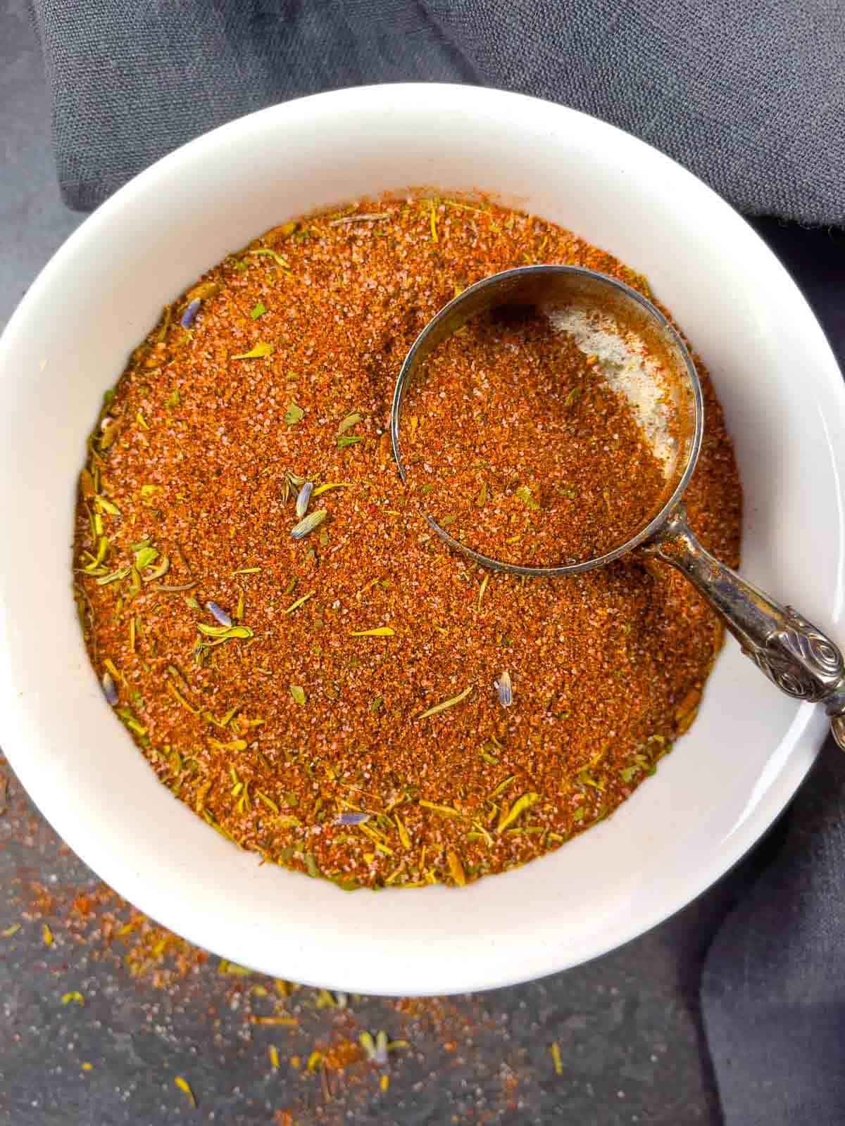 Barbeque rub in a small white bowl with a scoop.