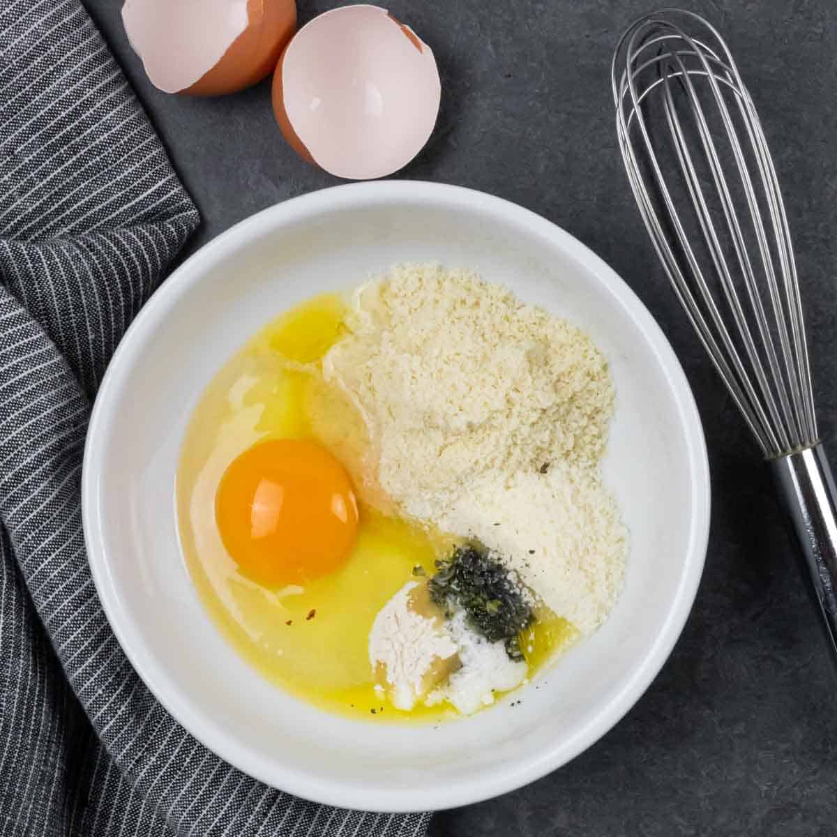 Melted butter in a small white bowl, with all remaining ingredients added and ready to combine with the whisk next to the bowl.  Caption with process step.